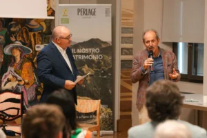 Due uomini discutono di vini biologici davanti a un banner di Perlage Winery, Prosecco DOCG.