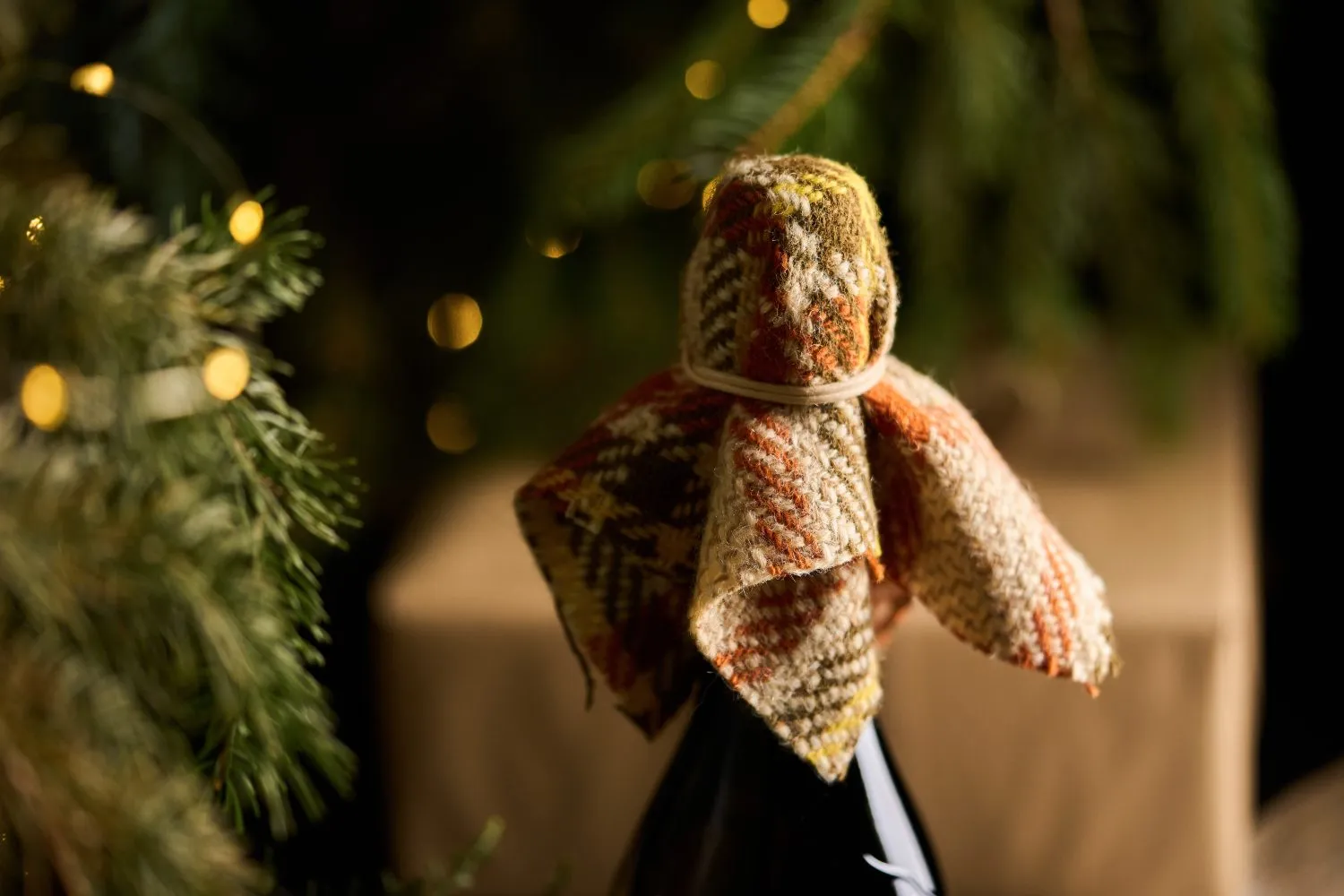 Bottiglia di vino vestita a festa tra luci natalizie, ideale per vini biologici e Prosecco DOCG.
