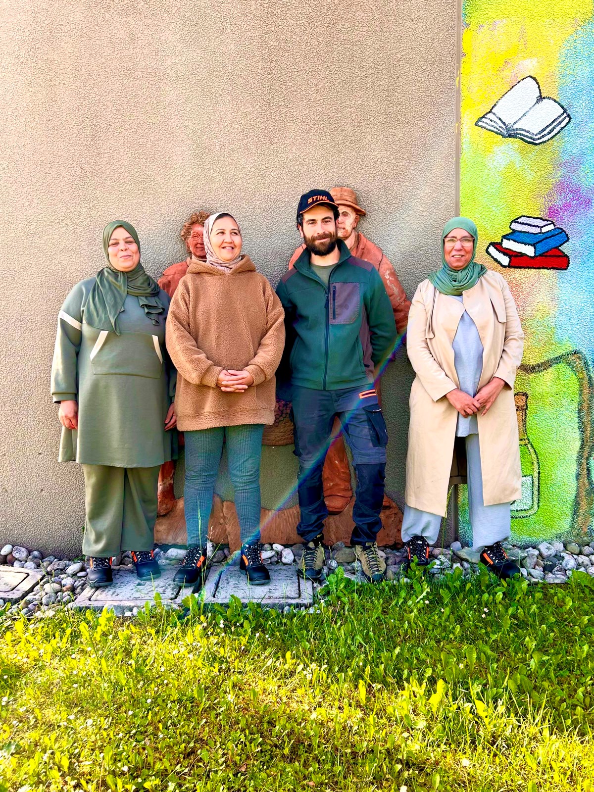 Four smiling people in front of a colorful mural in an environment reminiscent of Prosecco DOCG.