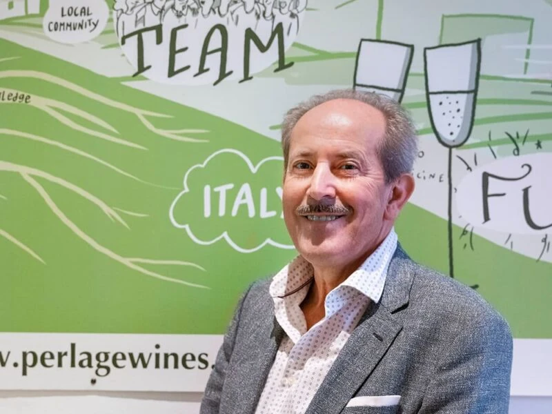 perlage-v-come-vegani Persona sorridente presso uno stand di vini biologici, riferimenti a Perlage e Prosecco DOCG Conegliano.